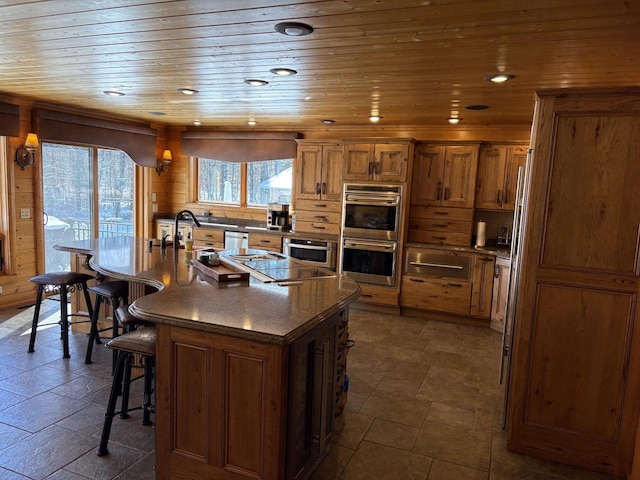 kitchen featuring recessed lighting, appliances with stainless steel finishes, wooden ceiling, a kitchen breakfast bar, and brown cabinets