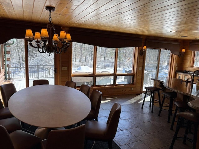 dining area with a chandelier, stone tile floors, wooden ceiling, and a healthy amount of sunlight