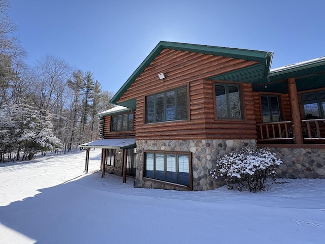 view of snowy exterior featuring stone siding