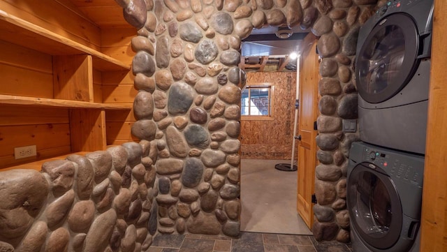 wine area with stacked washer and dryer and stone finish floor