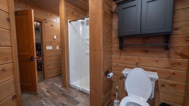 bathroom featuring a shower with curtain, wooden walls, wood finished floors, and toilet