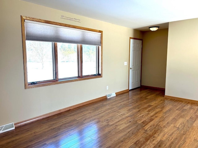 empty room with visible vents, baseboards, and wood finished floors