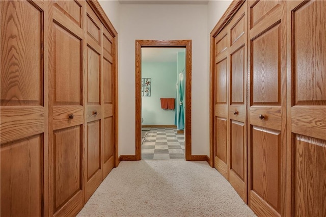 corridor with baseboards and light colored carpet