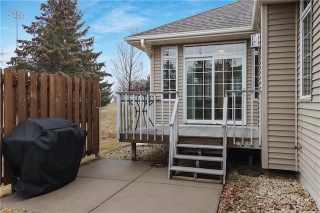 view of patio with a grill, a deck, and fence