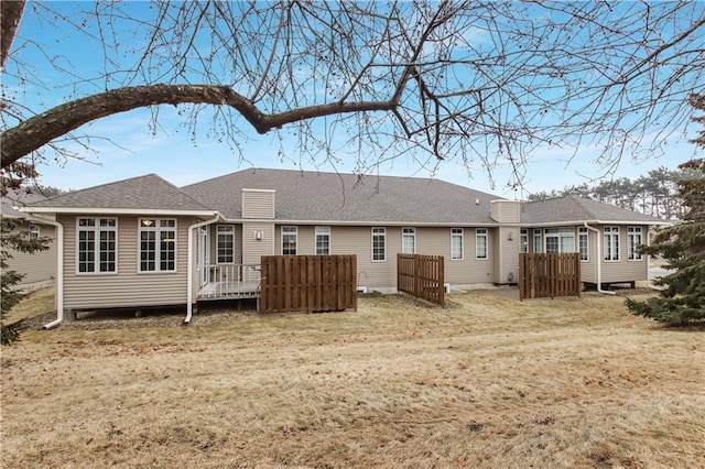 back of house with a yard and roof with shingles