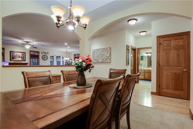 dining area with ceiling fan with notable chandelier and light wood finished floors