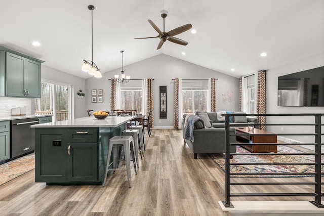 kitchen with light wood finished floors, light countertops, green cabinets, vaulted ceiling, and dishwashing machine