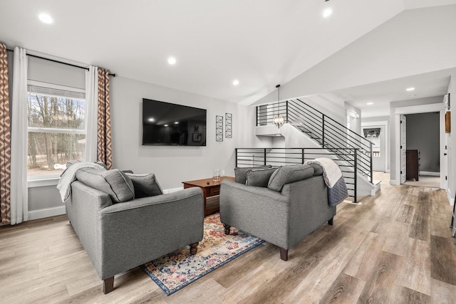 living area with light wood-style floors, recessed lighting, vaulted ceiling, and stairs