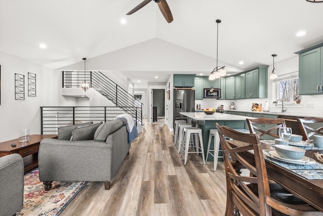 living room featuring a ceiling fan, lofted ceiling, stairway, light wood-type flooring, and recessed lighting