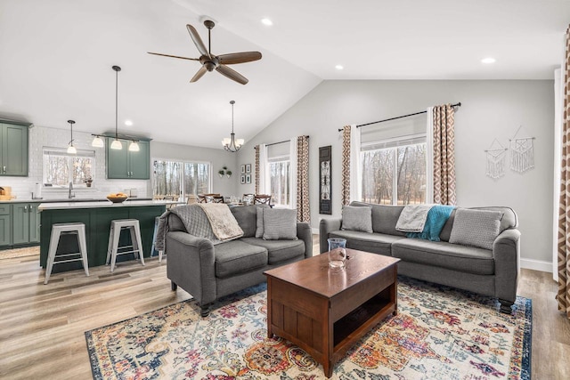 living area with lofted ceiling, ceiling fan with notable chandelier, light wood-style flooring, and recessed lighting