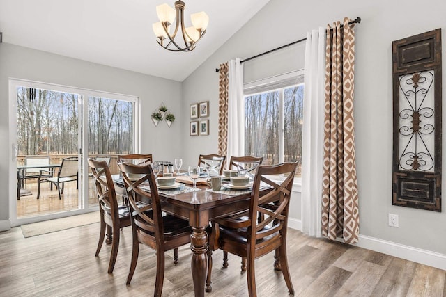 dining room featuring light wood-type flooring, lofted ceiling, baseboards, and an inviting chandelier