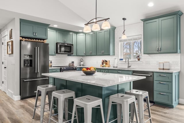 kitchen featuring lofted ceiling, green cabinets, appliances with stainless steel finishes, and a kitchen breakfast bar