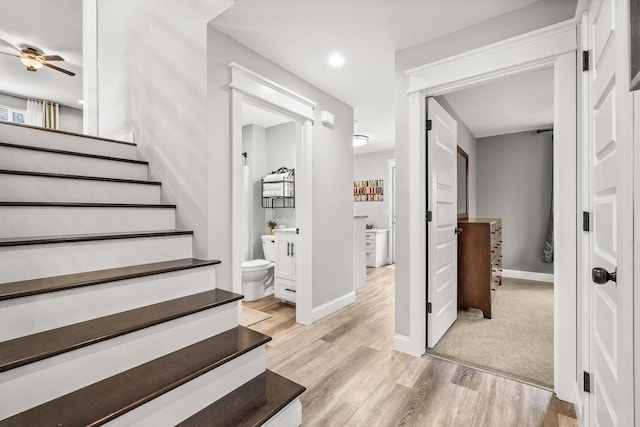 stairway with ceiling fan, baseboards, and wood finished floors