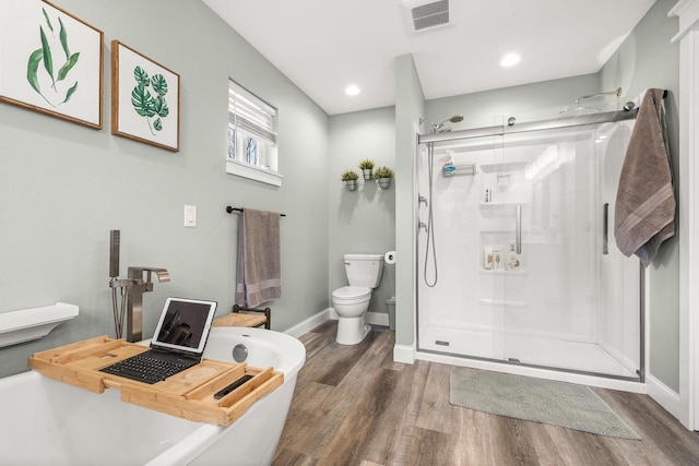 bathroom featuring toilet, wood finished floors, visible vents, a soaking tub, and a stall shower