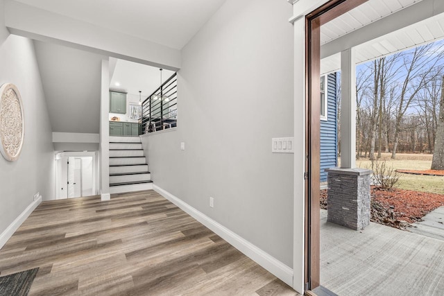 foyer entrance with stairs, wood finished floors, and baseboards