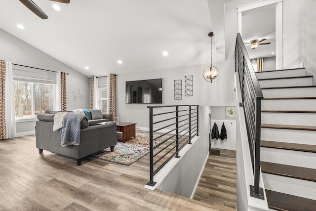 living area featuring lofted ceiling, recessed lighting, wood finished floors, baseboards, and ceiling fan with notable chandelier