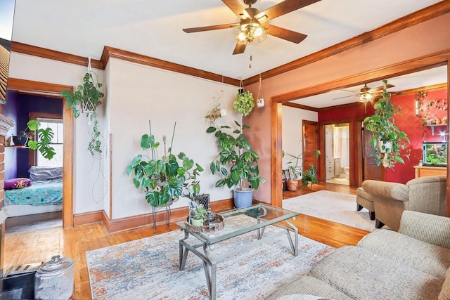 living area with ornamental molding, wood finished floors, a ceiling fan, and baseboards