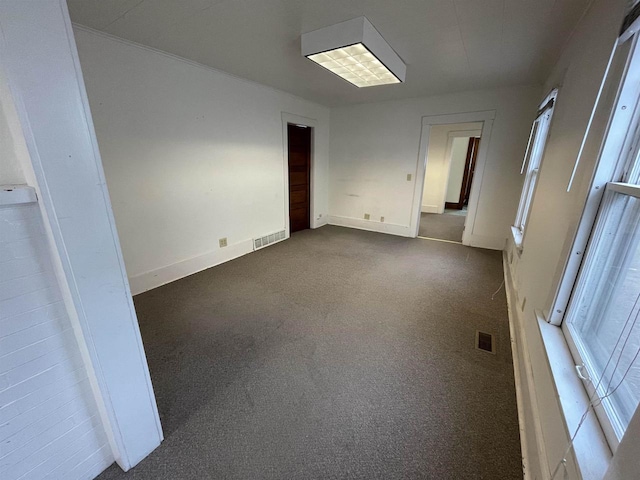 unfurnished room with baseboards, visible vents, and dark colored carpet