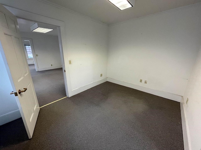 unfurnished room with baseboards, dark carpet, and crown molding