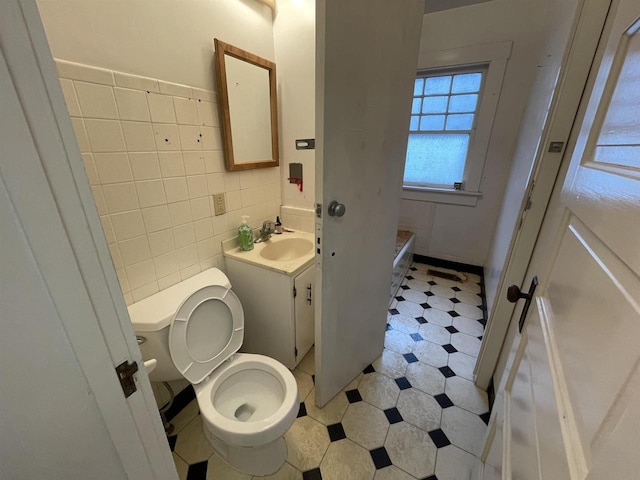 bathroom featuring toilet, vanity, tile walls, and tile patterned floors