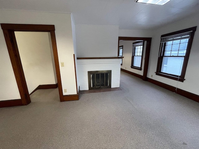 unfurnished living room featuring carpet, a brick fireplace, and baseboards