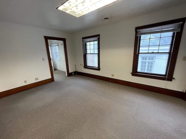 empty room with carpet flooring, visible vents, and baseboards