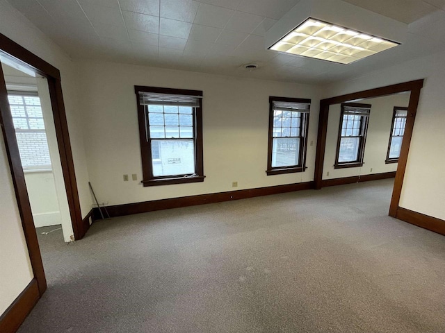 carpeted spare room with visible vents, a wealth of natural light, and baseboards