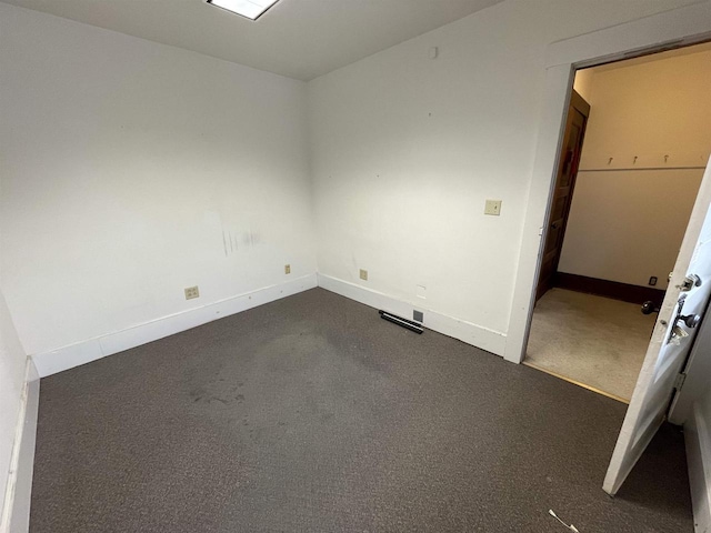 unfurnished room featuring baseboards and dark colored carpet