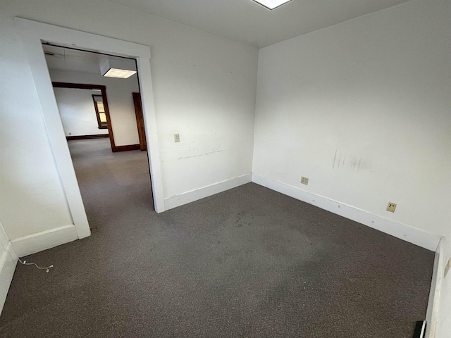 unfurnished room with dark carpet and baseboards