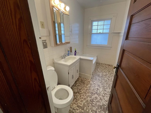 bathroom with toilet, a tub to relax in, tile walls, and vanity