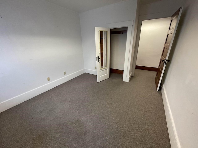 unfurnished bedroom featuring dark carpet and baseboards