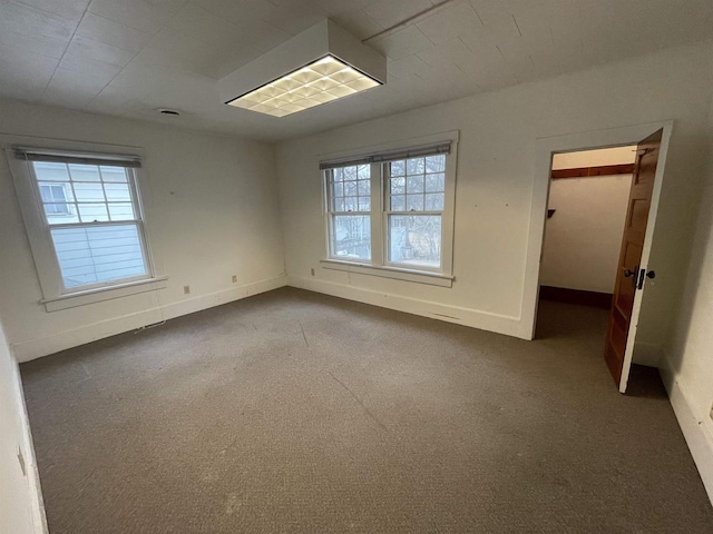 unfurnished room featuring carpet flooring, plenty of natural light, and baseboards