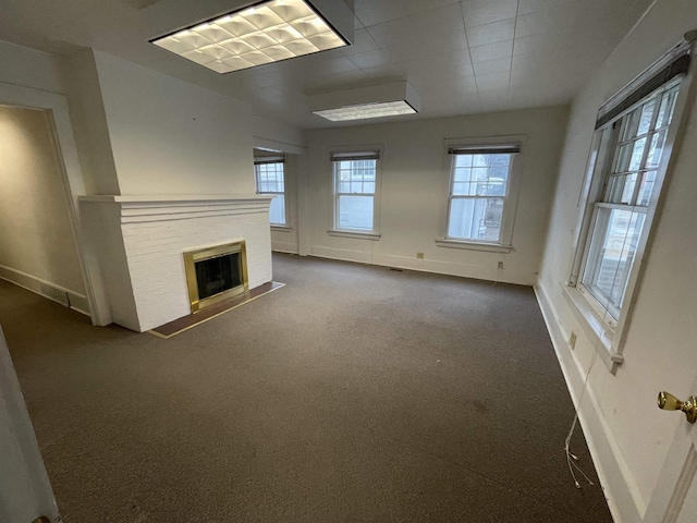 unfurnished living room featuring carpet, a brick fireplace, and baseboards