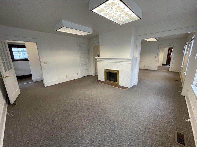 unfurnished living room featuring carpet floors, a brick fireplace, baseboards, and visible vents