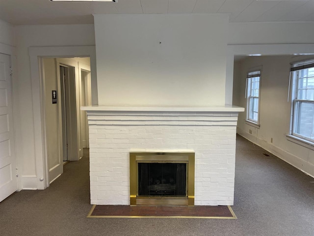 unfurnished living room featuring a fireplace, dark carpet, and baseboards