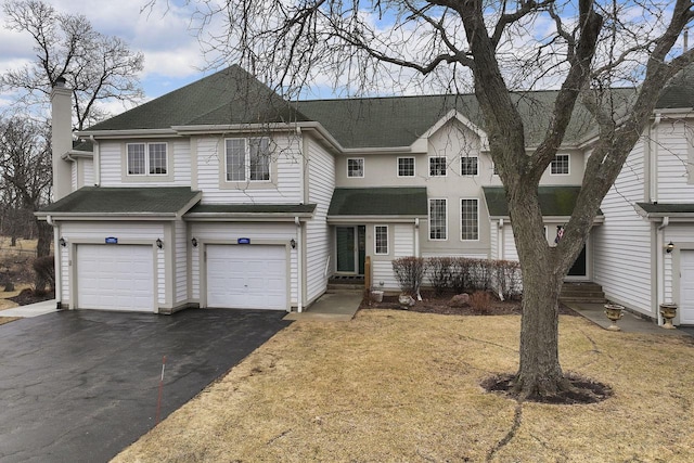 view of front of house with aphalt driveway, roof with shingles, a chimney, an attached garage, and entry steps