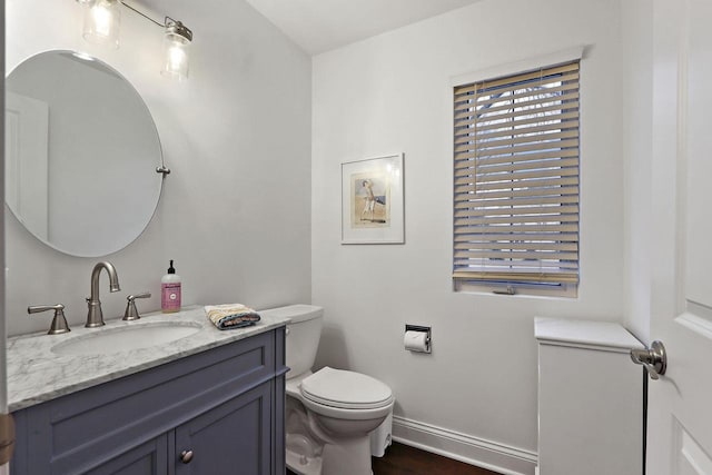 bathroom featuring wood finished floors, vanity, toilet, and baseboards