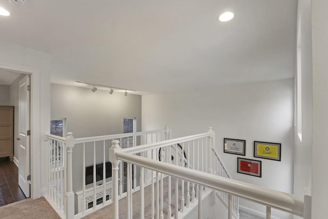 hall with recessed lighting, rail lighting, an upstairs landing, and wood finished floors