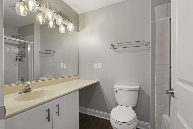 full bath with baseboards, toilet, wood finished floors, a tile shower, and vanity