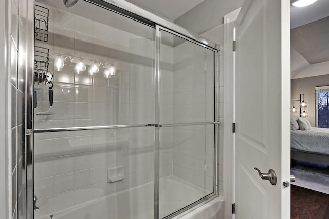 ensuite bathroom featuring enclosed tub / shower combo, ensuite bath, and wood finished floors