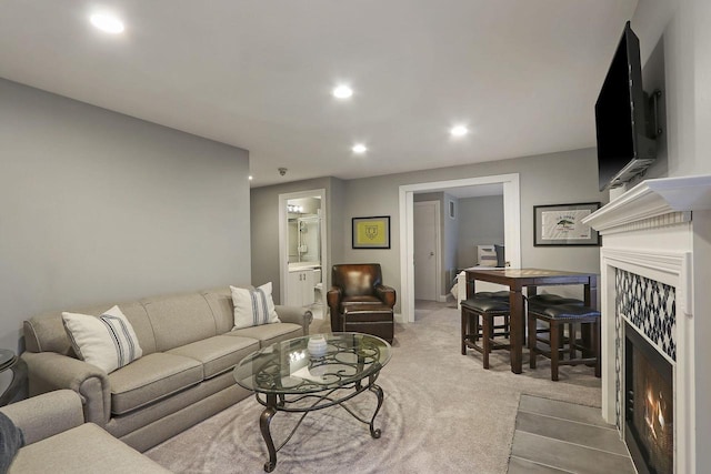 carpeted living area with a warm lit fireplace and recessed lighting