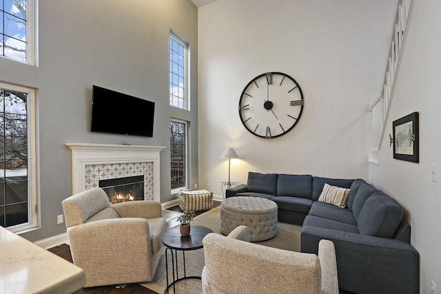 living area with a wealth of natural light, a tiled fireplace, and wood finished floors