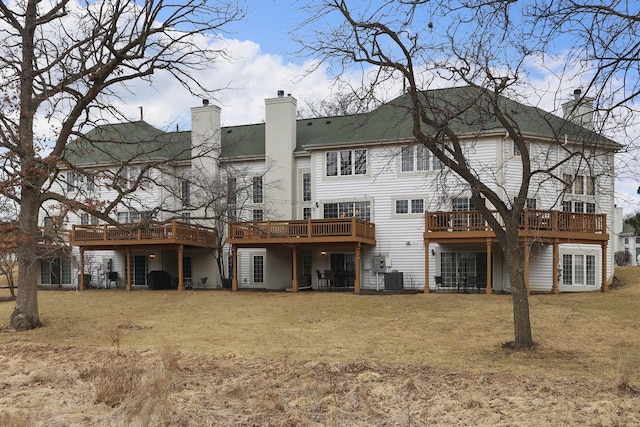 rear view of house with a deck, a yard, a chimney, and cooling unit