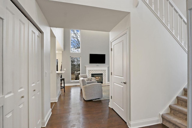 corridor with dark wood-style floors, a high ceiling, stairway, and baseboards