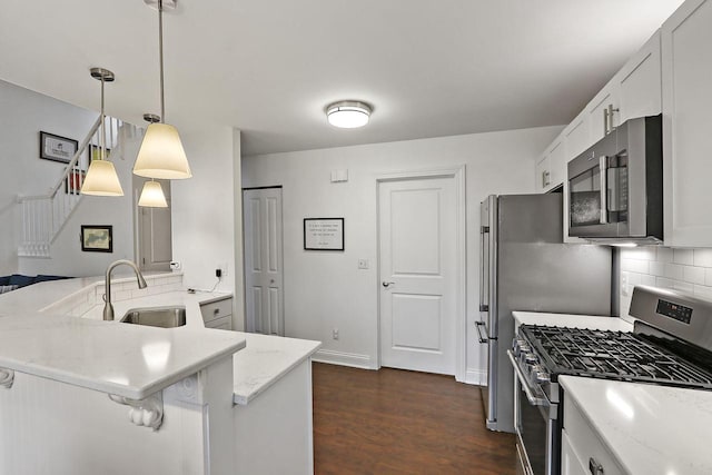 kitchen with decorative backsplash, light stone counters, appliances with stainless steel finishes, dark wood-type flooring, and a sink