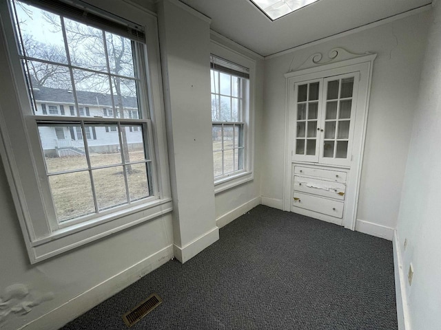 unfurnished room with visible vents, dark carpet, and baseboards