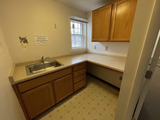 kitchen featuring light floors, a sink, light countertops, and brown cabinets