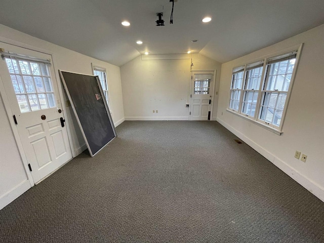 entryway featuring plenty of natural light, vaulted ceiling, dark carpet, and baseboards