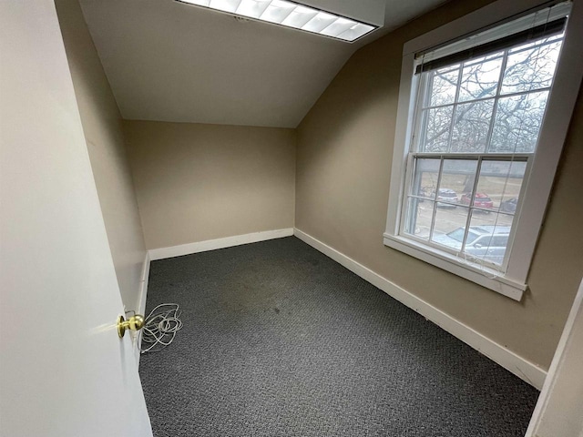 additional living space with baseboards, dark colored carpet, and a wealth of natural light