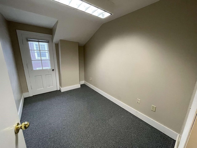 additional living space featuring lofted ceiling, baseboards, and dark carpet